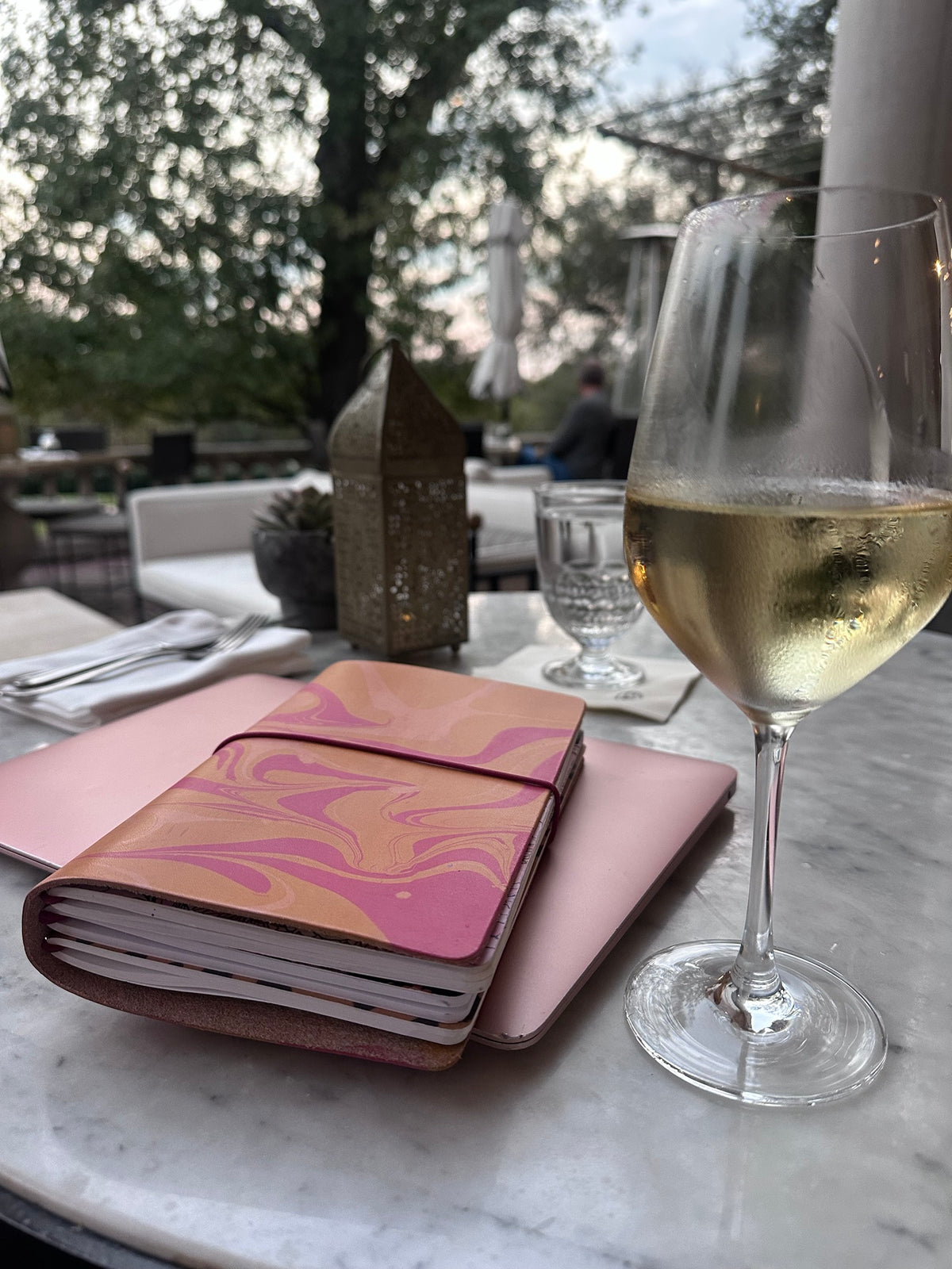 Pink and tan marbled leather folio holding several Classic Notebooks on a patio table