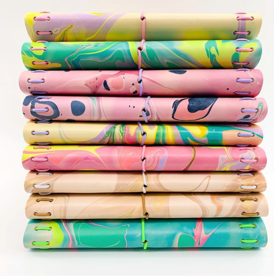 Stack of hand-marbled leather folios in pinks, greens and creams